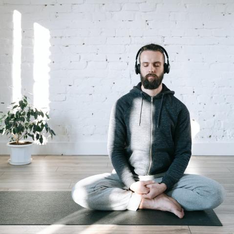 Man wearing headphones meditating on a yoga