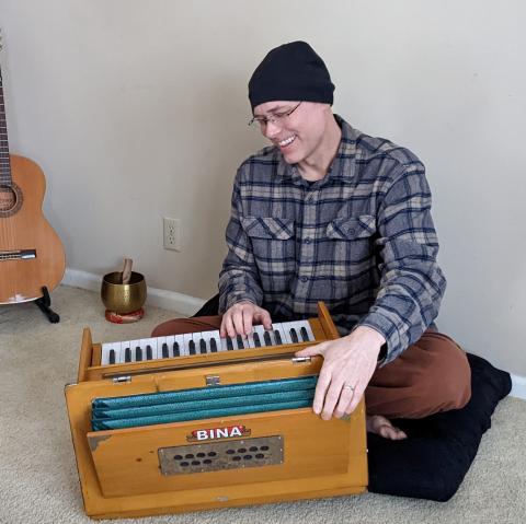 Matthew playing harmonium in the living room