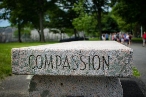 Gray concrete bench with the word compassion on the side