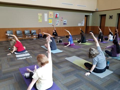 Matthew teaching yoga at the chanhassen library on May 22, 2023. Matthew and the class are doing a seated side bend.