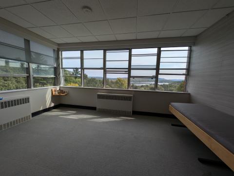 A corner room with lots of windows on two sides and a bench on the other, overlooking lots of forest and mountains