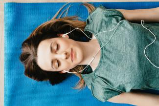 woman laying on a yoga mat with ear buds