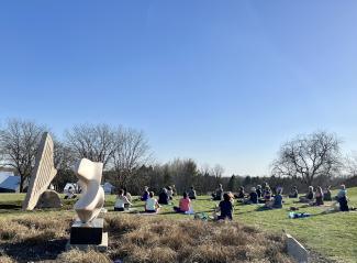 people sitting on yoga mats in the sculpture gardens