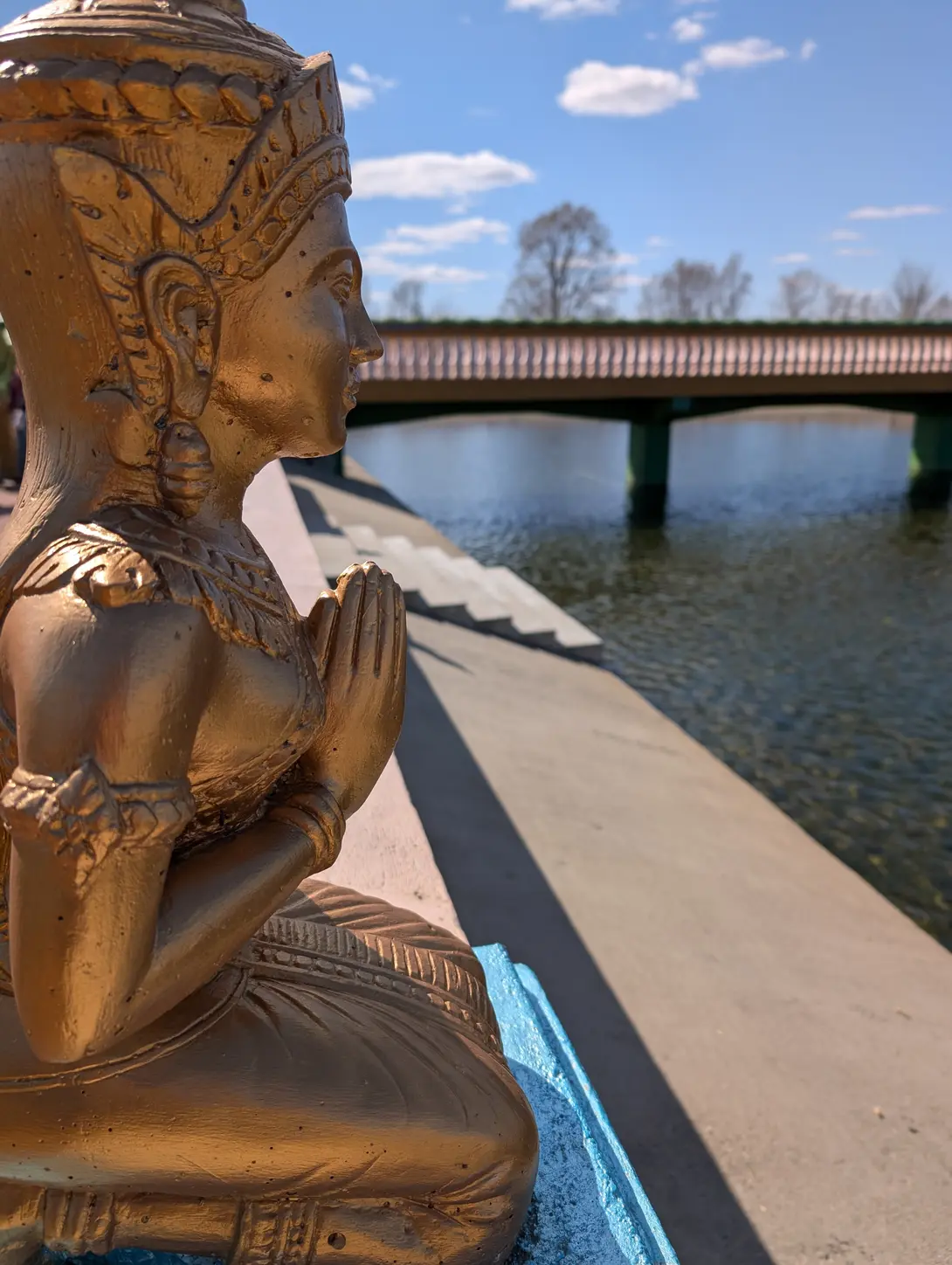 gold cambodian budda statue by a lake