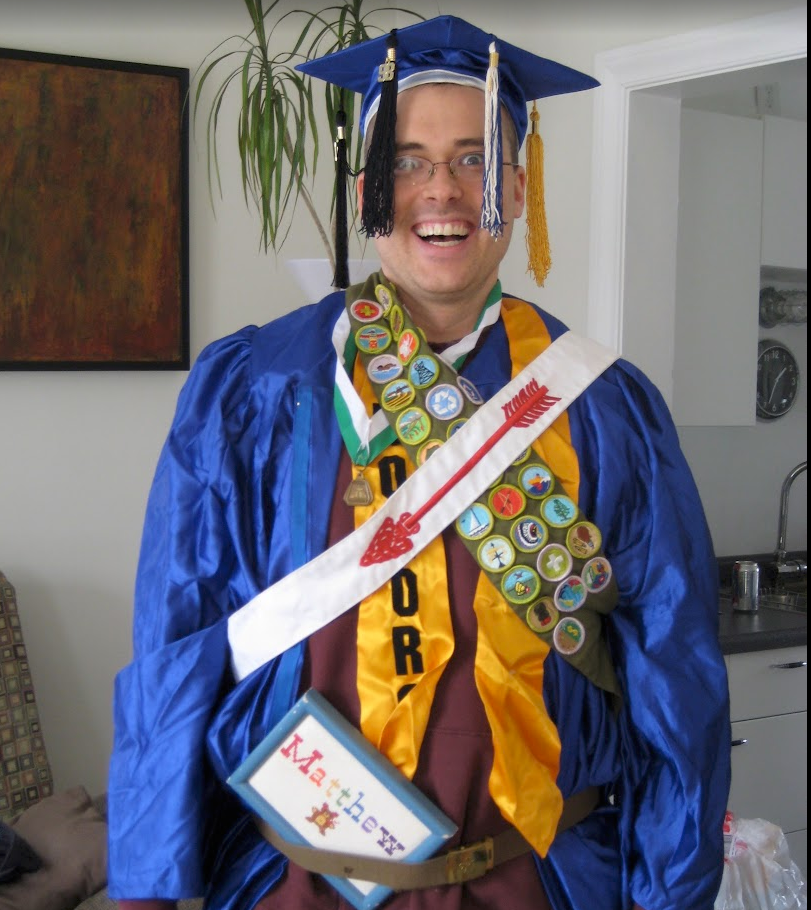 Matthew wearing a graduation gown, order of the arrow stash, boy scout merit badge stash, and lots of other silly graduation gear
