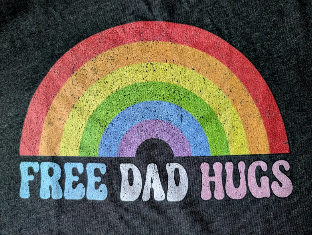 the text free dad hugs under a rainbow on a gray background