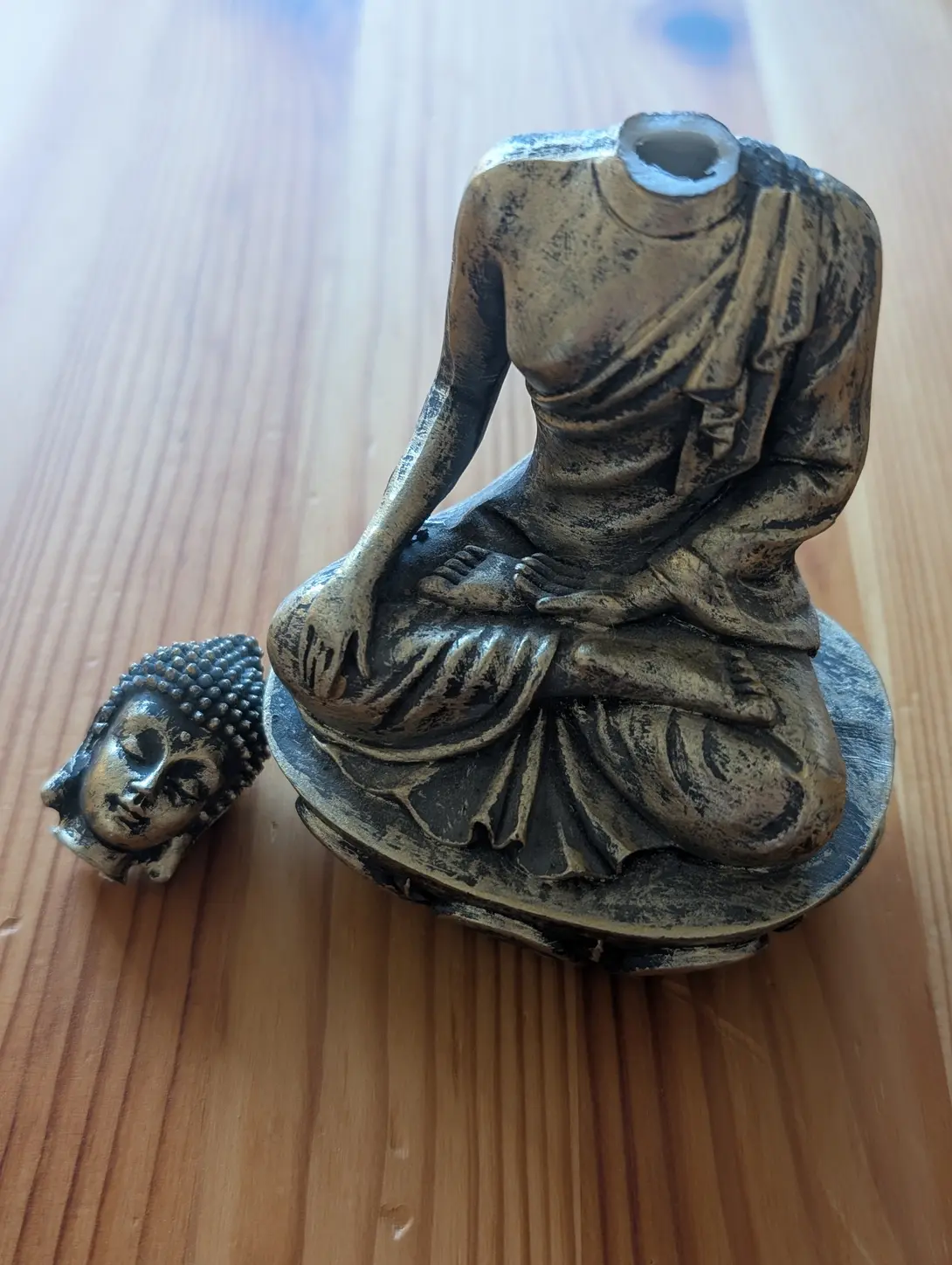 buddha statue with a broken head on a wooden surface