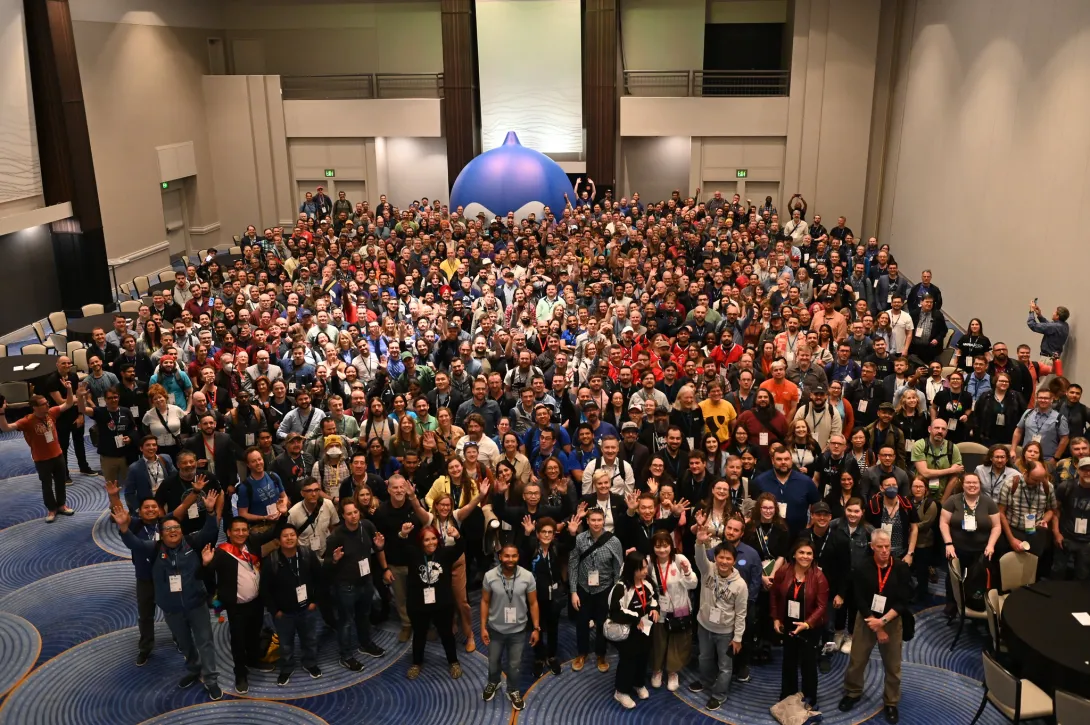 Group photo from DrupalCon Atlanta 2025 with lots of people and an inflatable blue Druplicon